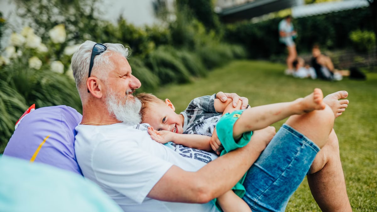 A joyful moment between a grandfather and grandson relaxing outdoors on a sunny day.